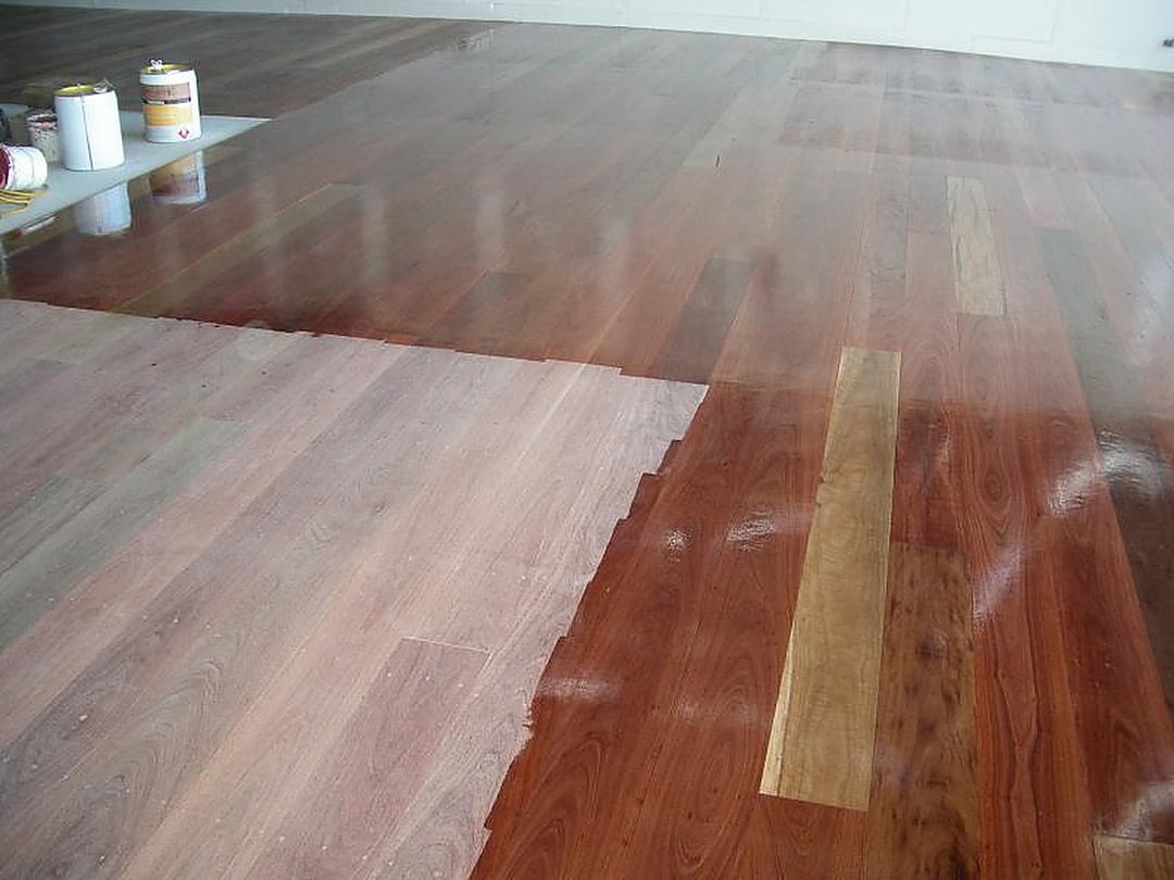 Fresh coating being applied — raw sanded boards beside wet polished timber